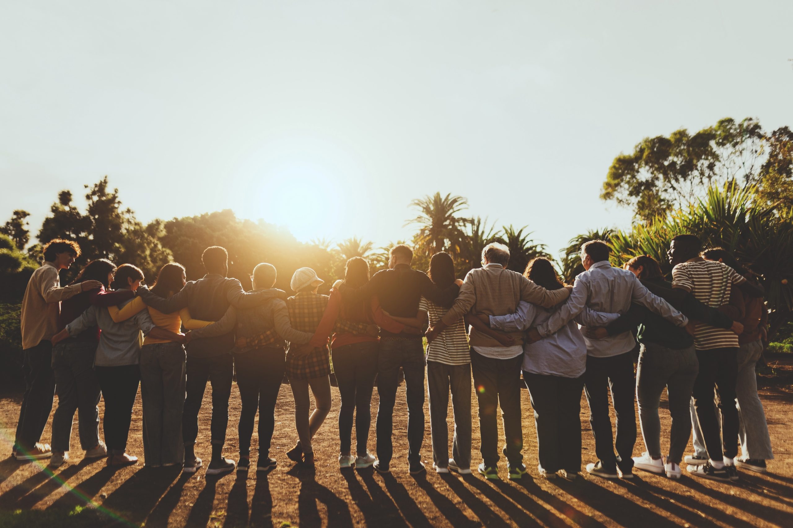 Back view of happy multigenerational people having fun in a public park during sunset time - Community and support concept